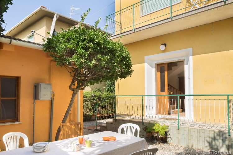 Uteplassen til Vera. Inngangen til leiligheten i bakgrunnen. Bildet viser feriehus ved sjø og strender nært Pisa i Toscana.