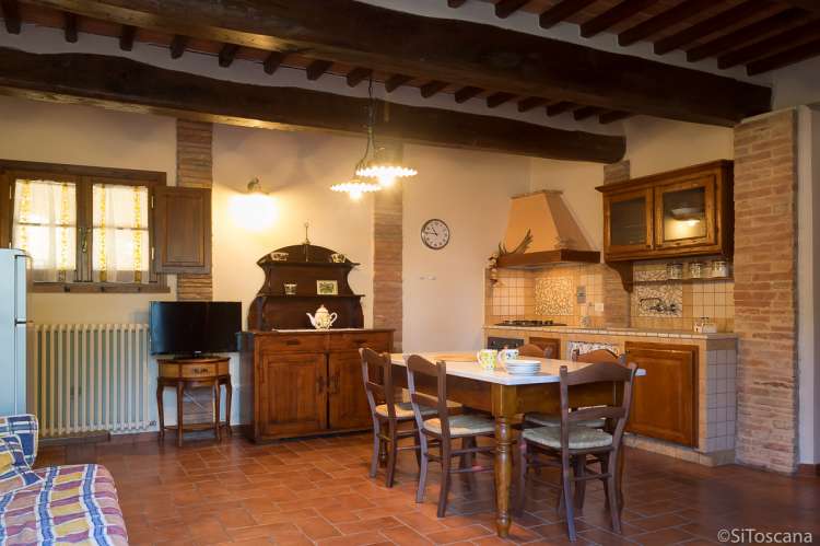 Tre Civette har sovesofa og plass til ekstraseng i oppholdsrom/kjøkken. Bildet viser kjøkken med spisebord i feriebolig på vingård i hjertet av Toscana.
