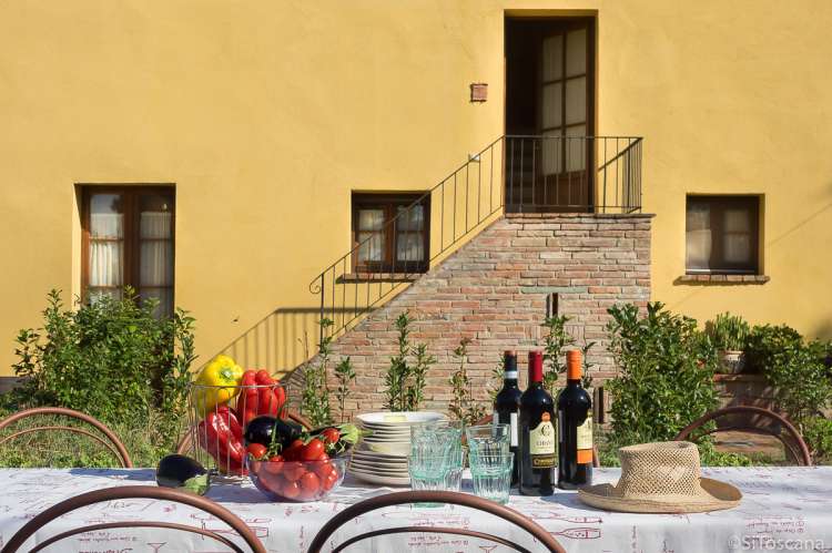 Domani è Festa har uteplass på bakkeplan. Trappa opp til leiligheten i bakgrunnen. Bildet viser oppdekket bord på uteplass utenfor ferieleilighet midt mellom Pisa og Firenze.