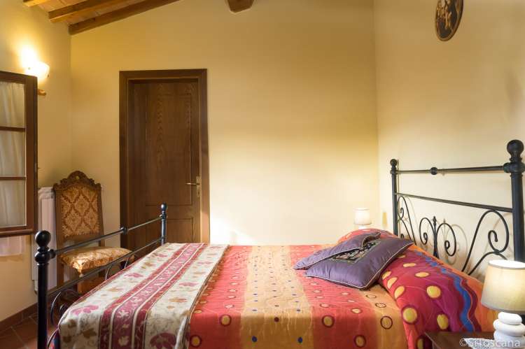 Bildet viser soverom med dobbeltseng i feriebolig på vingård nært Pisa.