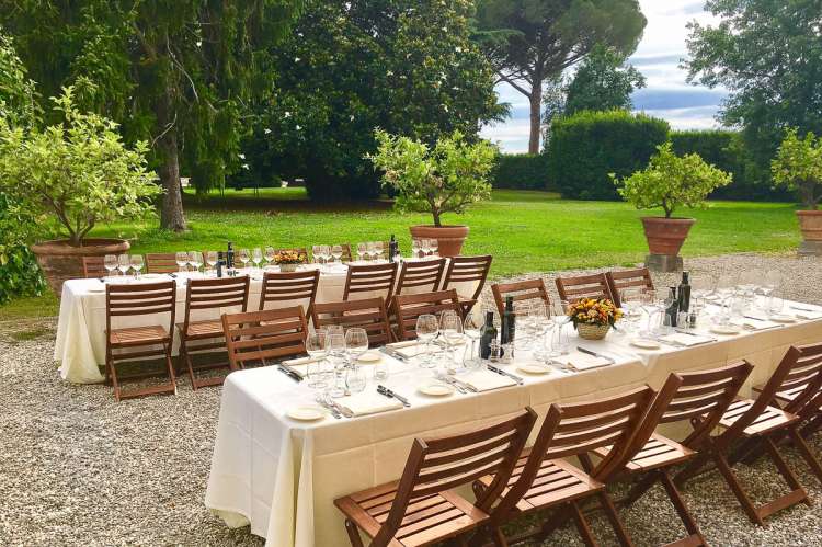 Bildet viser to langbord utenfor stort feriehus ved Pisa i Italia.