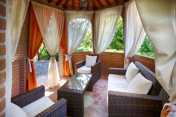 Bildet viser lysthus med sofa på feriebosted ved landsby i Toscana.