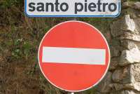Bildet viser to skilt, ett med gatenavnet Via Santo Pietro og ett med Innkjøring forbudt. Skiltet og veien befinner seg i landsbyen Calci, like utenfor Pisa.