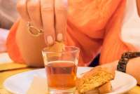 Bildet viser en kvinnehånd som dypper kjeksen Cantuccini i Vin Santo. Bildet er fra spisestedet Trattoria di Montemagno, like utenfor Pisa.