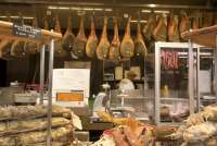 Bildet viser skinker som henger i taket, samt pølser og spekemat lagt opp for salg i Matmarkedet i Firenze – Mercato Centrale