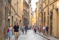 Bildet viser mennesker som går i en rolig gate nesten uten trafikk i Firenze sentrum. I Toscana, i Italia.