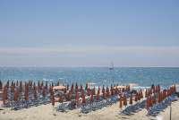 Bildet viser en av bagnoene i badebyen Tirrenia. Solstoler og parasoller på rekke og rad med Middelhavet glitrende i bakgrunnen. En seilbåt sees i horisonten.