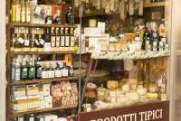Bildet viser vin, olivenolje og andre godsaker i et utstillingsvindu i en vin- og delikatessebutikk i Lucca.