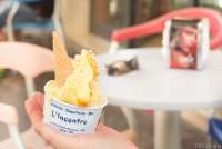 Bildet viser ei hånd som holder et pappbeger med italiensk is på en isbar i landsbyen Calci.