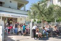 Bildet viser barn som er samlet på en isbar i Calci. De leker, prater og spiser is.