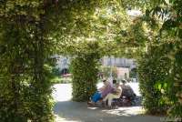 Bildet viser folk som sitter på en benk og hviler seg på Piazza Vittotio Emanuele II, like ved handlegata Corso Italia i Pisa.