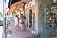 Bildet viser an av butikkene i hovedgata i Tirrenia. Utenfor står en mann sammen tre unge jenter. På skiltet over døra står det papirhandel, skole og kontor, mobiltelefoner.