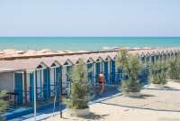 Fra en av bagnoene i badebyen Tirrenia. Badehus eller omskiftingsrom på rekke og rad. Volleyball bane i forgrunnen.