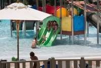 Bildet viser voksne og barn som leker i en av de små vannskliene i barnebassenget på Sunlight Park i Tirrenia. 
