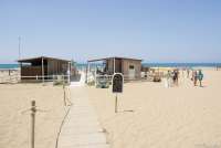 Bildet viser spisestedet og fasilitetene på fristranda Spiaggia Verruca i badebyen Tirrenia i Toscana. Til høyre i bildet sees mennesker på vei opp fra stranda. Stranda med Middelhavet i bakgrunnen. 