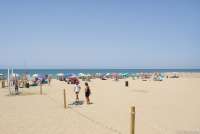 Bildet viser spiaggia libera på Spiaggia Verruca i badebyen Tirrenia. Du ser dusjfasilitetene, et tau som skiller fristranda fra der du kan leie parasoll etc. Folk som ligger under medbrakte parasoller. Og i bakgrunnen strandkanten og Middelhavet.