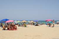 Bildet viser folk som ligger på stranda Spiaggia Verruca i Tirrenia. Det er sol, og nesten alle ligger under fargerike parasoller. I bakgrunnen ser du Middelhavet og strandkanten.
