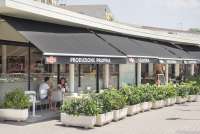 Bildet viser uteserveringen til et av spisestedene i sentrum av Tirrenia. Bordene er omkranset av grønne planter. Et par sitter ved et bord og spiser is.