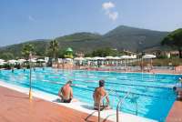 Bildet viser bassenget i La Gabella. To menn slapper av på bassengkanten. I bakgrunnen ser du vannskliene i et annet basseng.