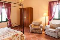 Bildet viser soverom med dobbeltseng og lenestoler i leiligheten Glicine på feriebostedet Girasole, vingård med 10 leiligheter og gangavstand til landsby.