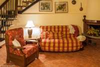 Bildet viser oppholdssrom med sofa, lenestol, peis samt trapp opp til 2. etg. i leiligheten Edera på feriebostedet Girasole, vingård med 10 leiligheter og gangavstand til landsby.