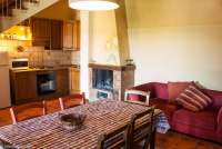 Bildet viser oppholdsrom med spisebord, kjøkken, peis og trapp opp til 2. etg. i leiligheten Girasole på feriebostedet Girasole, vingård med 10 leiligheter og gangavstand til landsby.