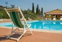 I bakgrunnen er uteserveringen til spistedet på gården. Bassenget med solstol på vingården Podere Cenni utenfor San Miniato. Foto.