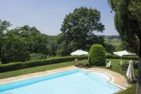 På Collina kan du slappe av i rolige, grønne omgivelser. Foto av bassenget med omgivelser på vingården. Sol, sommer og ferie i Toscana..