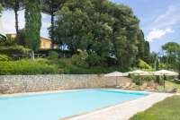 Et av de tre husene på gården skimtes over bassenget. Foto som viser plasseringen av bassenget nedenfor feriehusene på vingården.