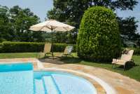 Det er vakre, grønne og rolige omgivelser på Collina. Bilde fra svømmebassenget på vingården. Grønt parkområde med solstoler.