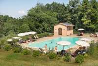 På bildet ser man voksne og barn som koser seg ved bassenget på vingården.