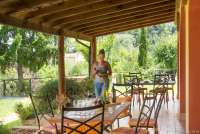 Bildet viser kvinne som dekker på langbord på terrassene utenfor ferieleilighetene Limone, Mela og Uva. På feriebostedet La Pergola, ved Pisa i Toscana.