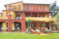 Bildet viser to kvinner som sitter på uteserveringen foran restauranten på feriebostedet La Pergola, ved Pisa i Toscana.