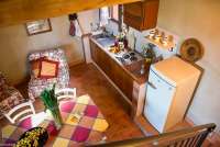 Bildet viser kjøkken med spisebord og kjøkkenbenker. Tatt fra trappa opp mot soverommet i 2. etg. I ferieleiligheten Fragola på La Pergola i Toscana.