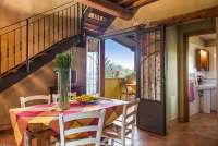 Bildet viser kjøkken med spisebord, trapp opp til soverom, glimt inn på badet og ut til terrassen med utsikt. I ferieleiligheten Fragola på La Pergola, ved Pisa i Toscana.