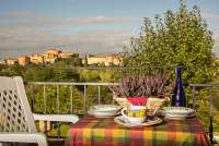 Bildet viser terrassen med spisebord og utsikt mot landsbyen fra ferieleiligheten Ciliegia. På feriebostedet La Pergola ved Pisa i Toscana.