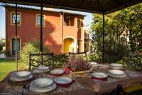 Bildet viser uteplassen til ferieleiligheten Nespola med spisebord og pergola ved Pisa i Italia.