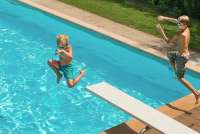 Bildet viser barn i full aktivitet i svømmebassenget, på stupebrett på vingården Borgo Etruschi sentralt i Toscana.