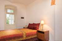 Bildet viser soverom med seng og dør i ferieleilighet i middelalderlandsby i Toscana.