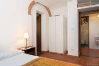 Bildet viser soverom med seng og inngang til baderom i ferieleilighet utenfor Pisa.