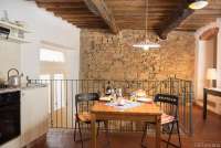 Bildet viser kjøkken med spisesbord og murvegg i ferieleiligheten Karine midt i middelalderlandsby i Toscana.