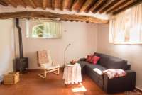 Bilde av stua med god dobbel sovesofa og typisk toskansk byggestil i ferieleiligheten Karine.. Vedovn til bruk i den kjølige sesongen.