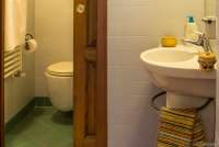 Foto fra badet som er delt i to, et rom med vask og skyvedør til toalett og dusj.  Dør fra to rom til badet.