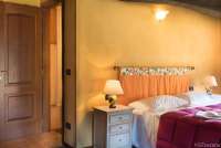 Bildet viser soverom med dobbeltseng og inngang til bad i feriehuset Casa Diana med privat basseng og hage ved Pisa.