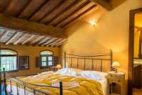 Bildet viser soverom med dobbeltseng og eget bad i det toskanske feriehuset Casa Diana i landsby med privat hage og basseng.