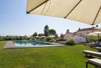 Bildet viser basseng og gressplen på feriebosted ved kysten i Toscana.