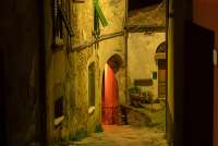 Steinhus med bue over den smale brosteinsgata i Montemagno. Kveldsbilde fra landsbygate. Steinhus med bue over den smale brosteinsgata.