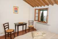 Naboens sypress kan skimtes fra vinduet i 2. etg Naboens sypress kan skimtes fra vinduet i ferieboligen. Soverom med lite bord og stoler. Bilde