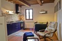 Oppholdsrom med kjøkken. Kjøkken med god standard i ferieleiligheten Casetta Livia. Spisebord og 2 lenestoler. Bilde.
