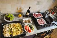 Festforberedelser på kjøkkenet. Feiring av årsdag med mat til et stort italiensk måltid på kjøkkenbenken. MFoto av mat og vin i Toscana.